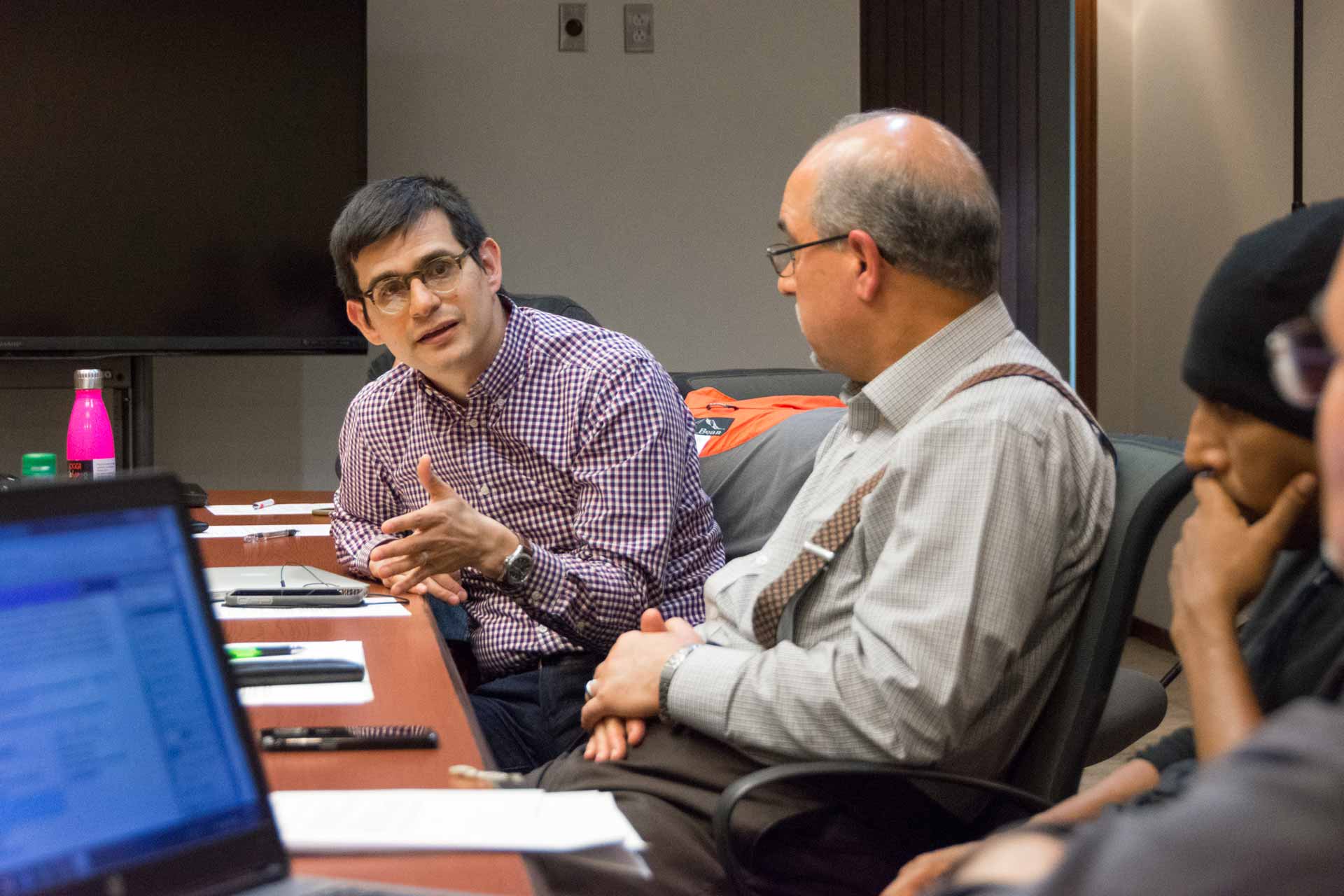 Faculty Members sitting together at talking at a conference table.